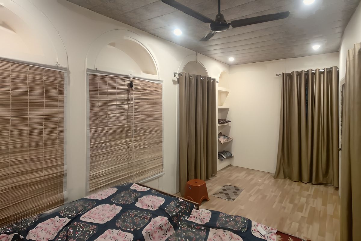 A room with arched windows, bamboo blinds and a ceiling fan
