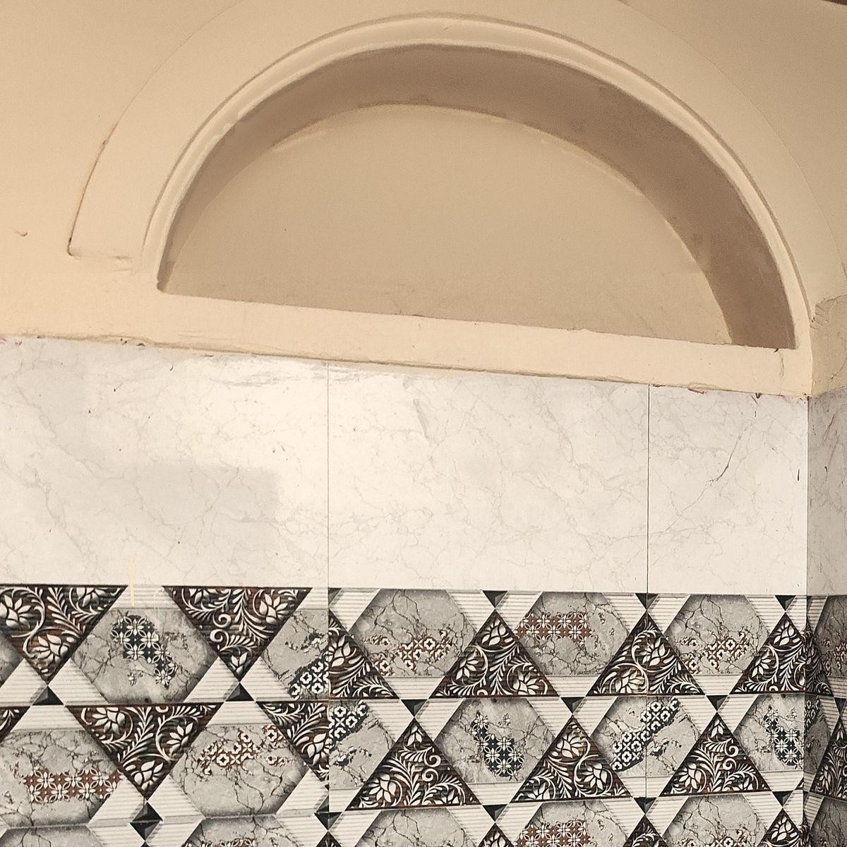 A plastered arch above patterned tiles in an attached bathroom